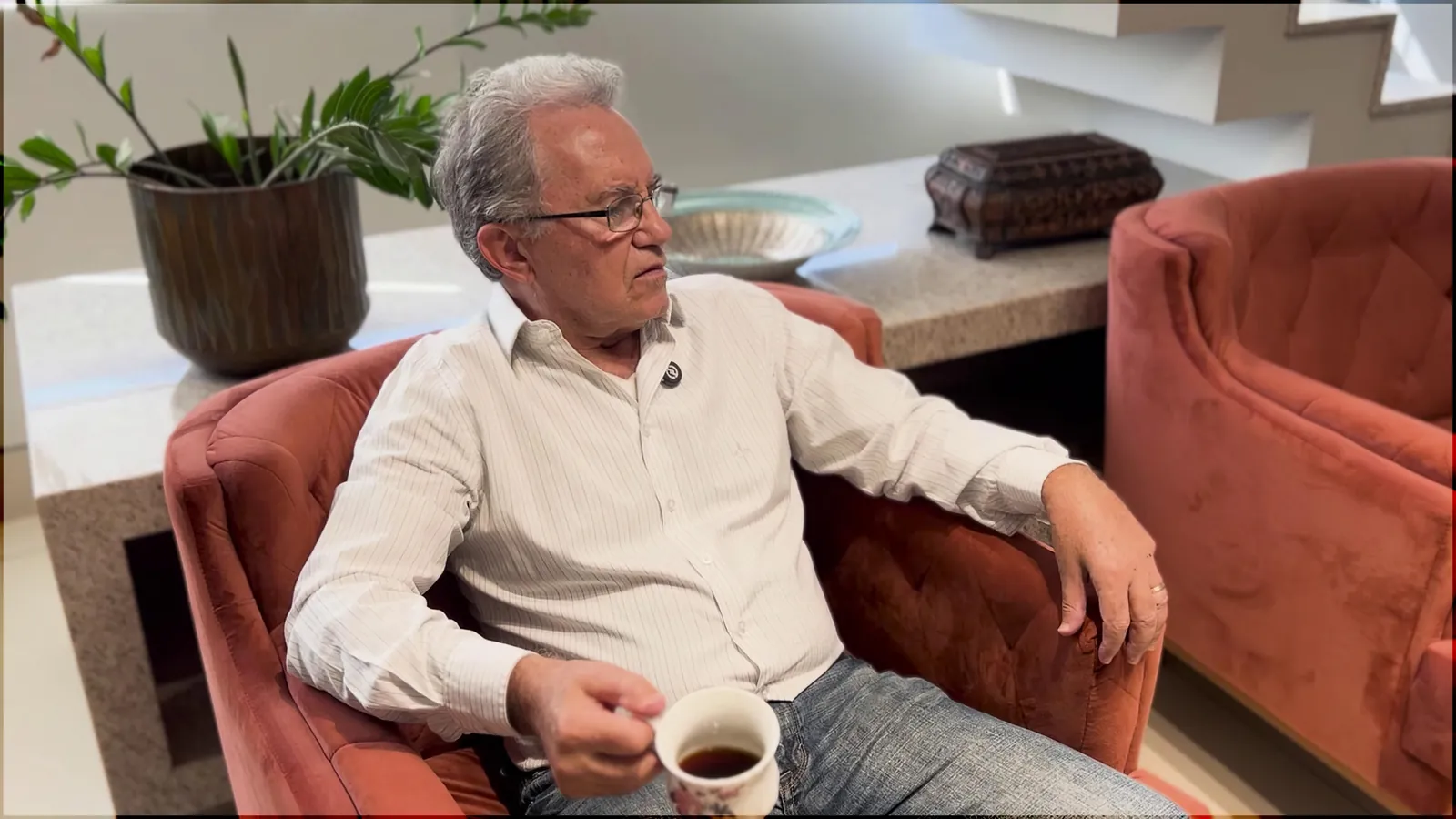 Braz Dias sentado em sua poltrona, com uma xícara de café