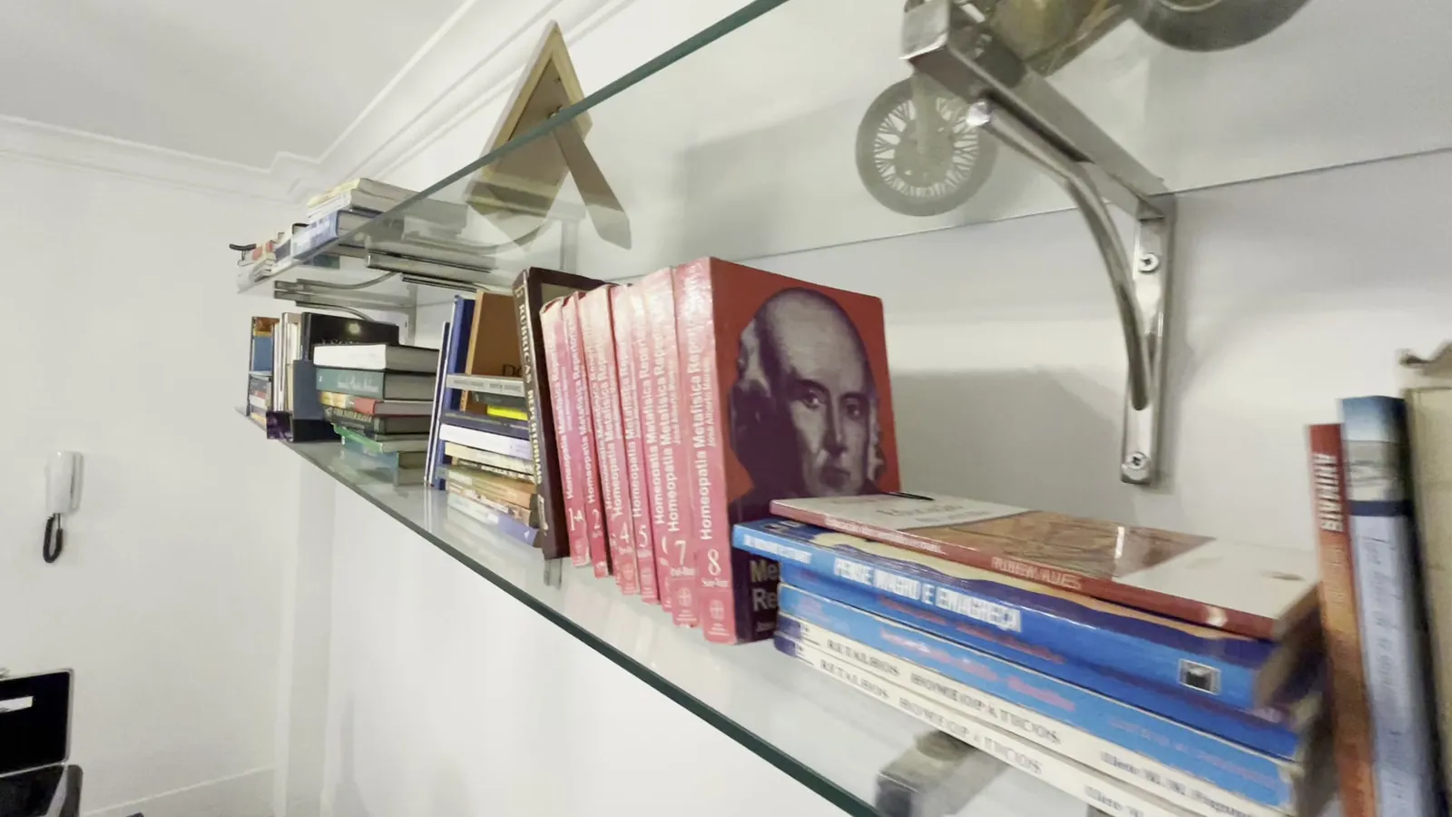 Estante com livros de homeopatia no consultório do Braz